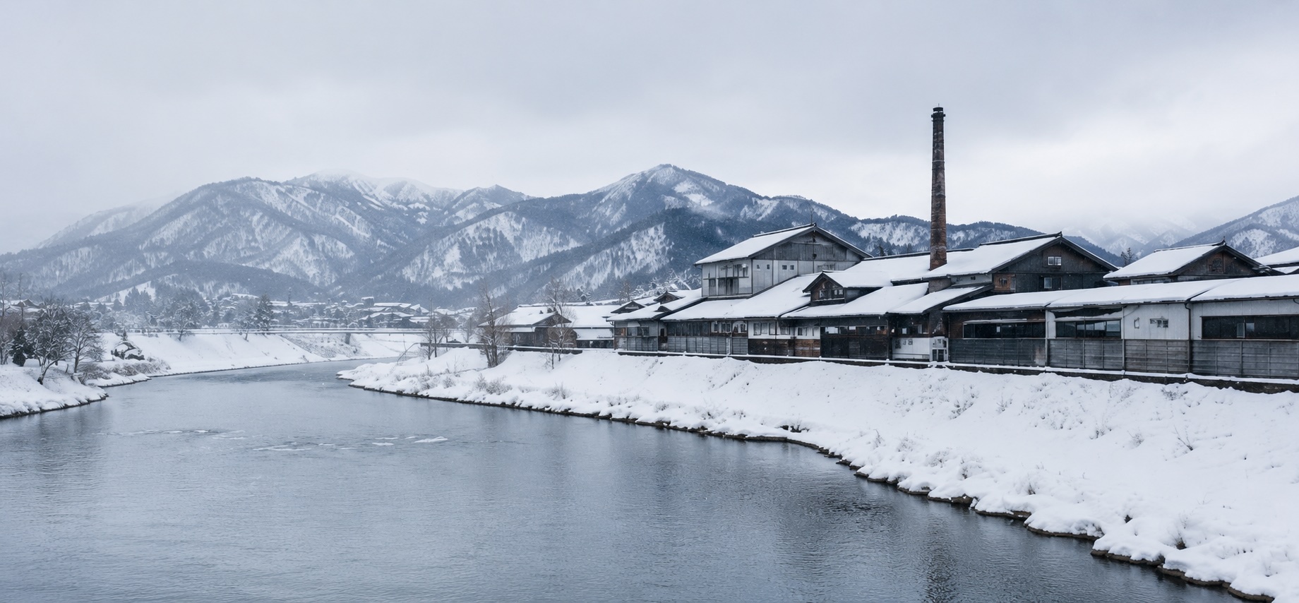 雪に包まれた長岡の川辺と蔵の町並み